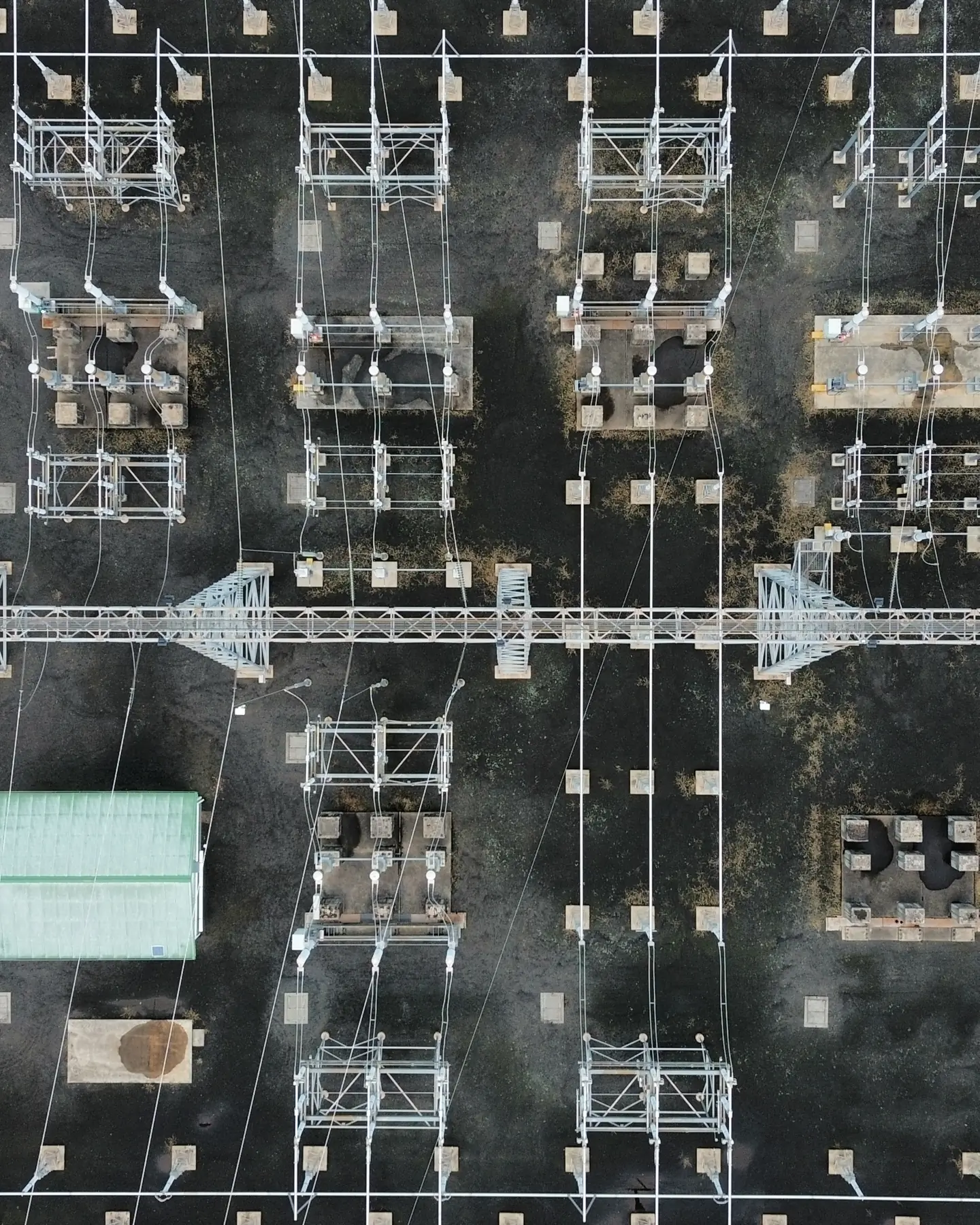 Overhead view of a substation switchyard, transformer bays and gantry steel laid out in a grid.