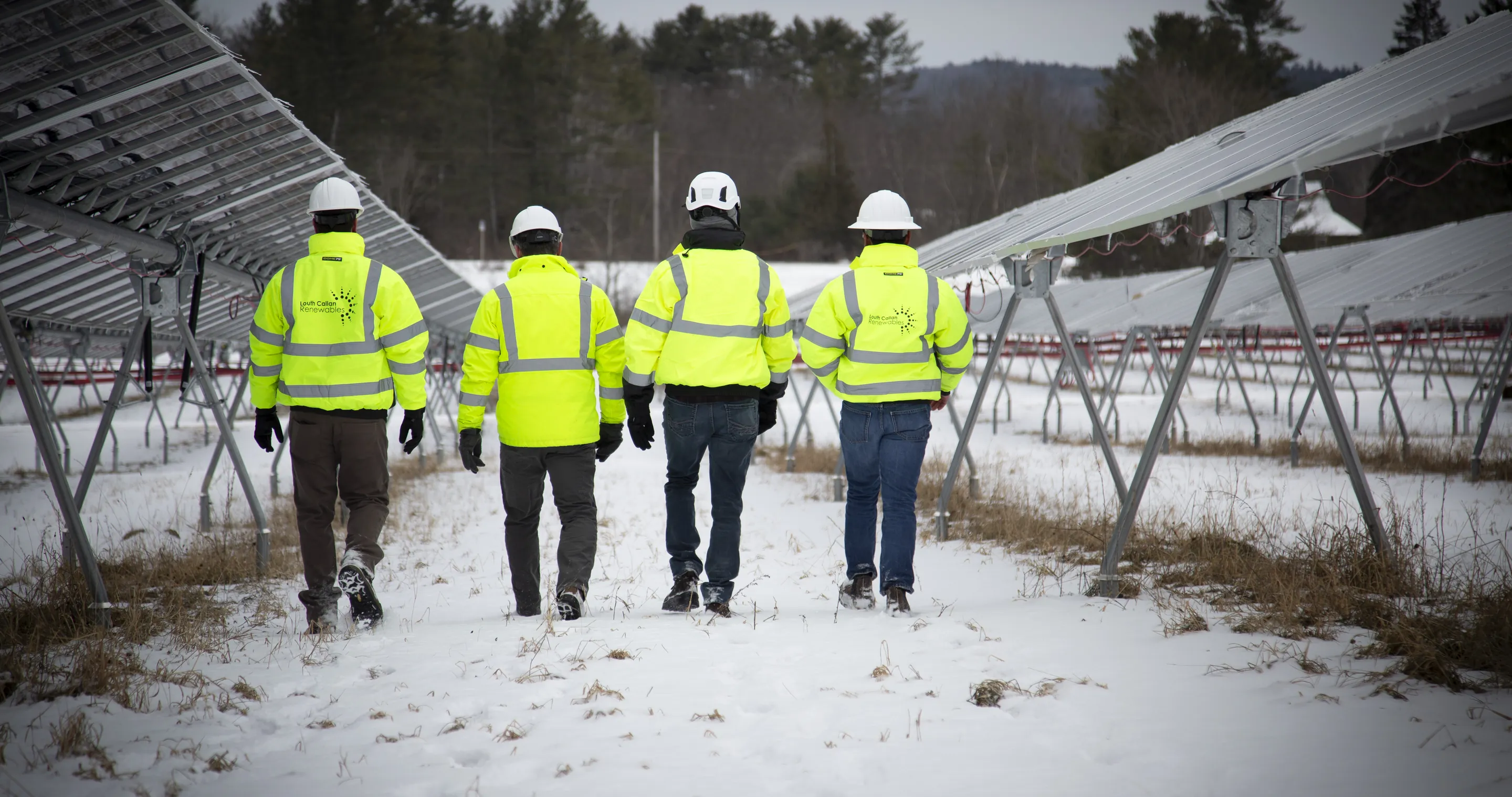 Four Louth Callan crew members walking a completed racking field in snow.
