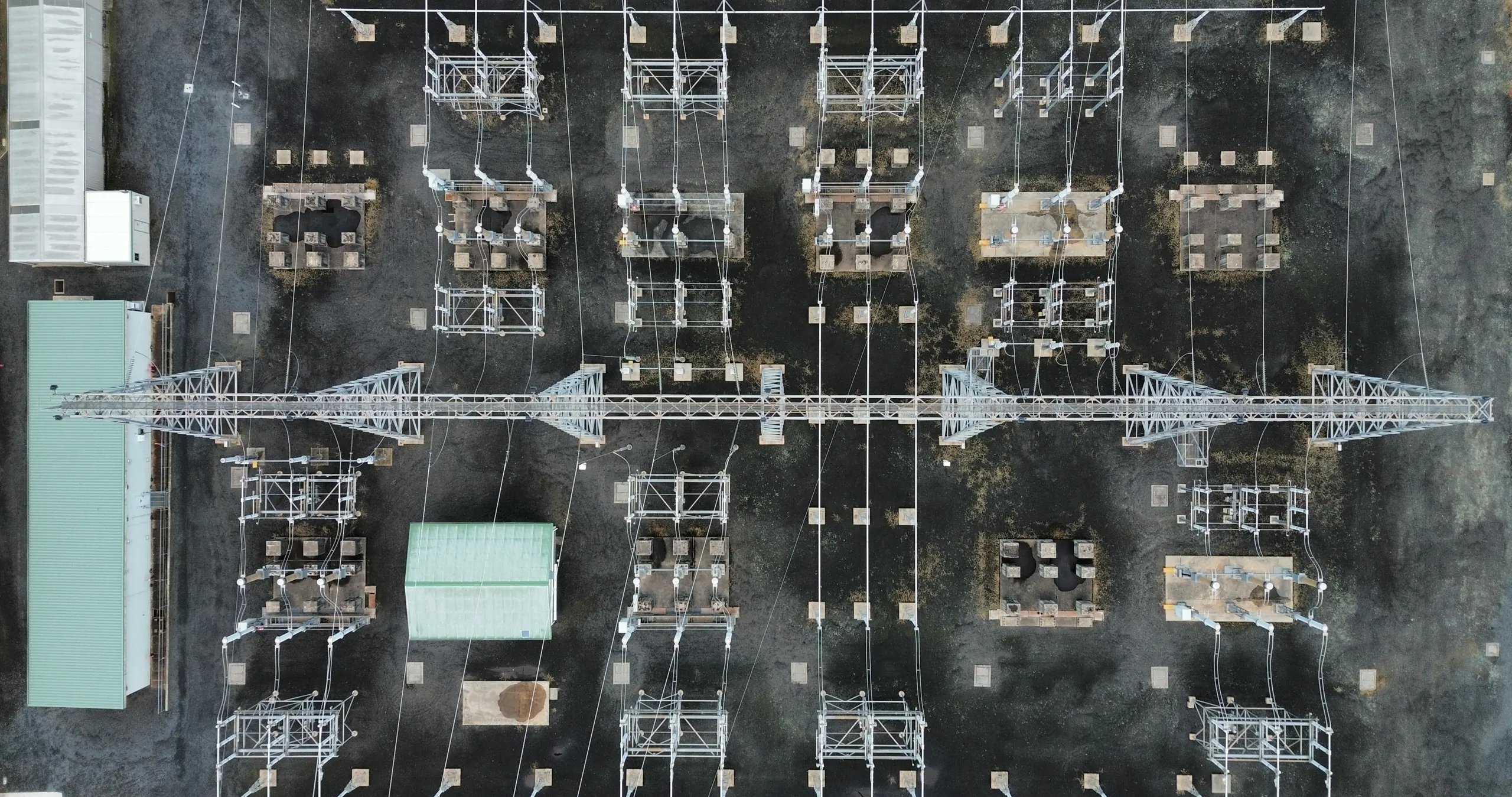 Overhead view of a high-voltage switchyard, with transformers, gantry steel and overhead bus laid out across the site.